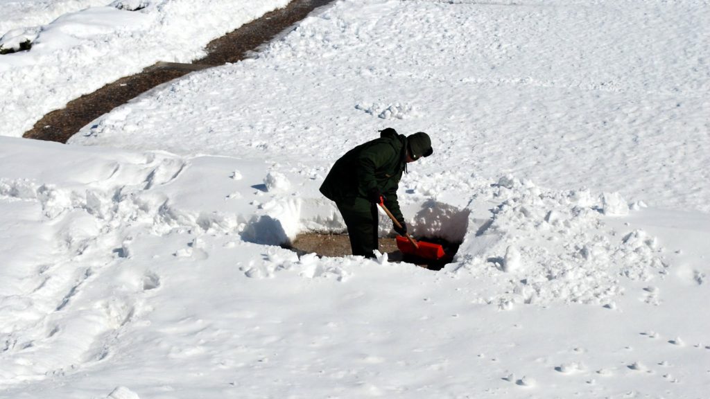 man shoveling snow off driveway 